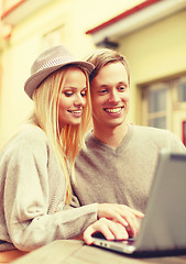 Image showing smiling couple with laptop computer in cafe