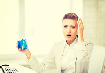 Image showing stressed businesswoman holding clock