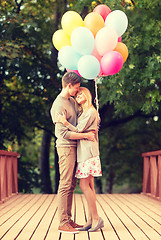 Image showing couple with colorful balloons kissing in the park