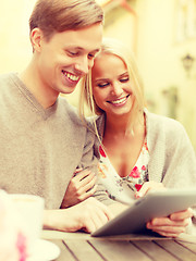 Image showing smiling couple with tablet pc computer in cafe