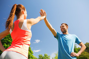 Image showing two smiling people making high five outdoors