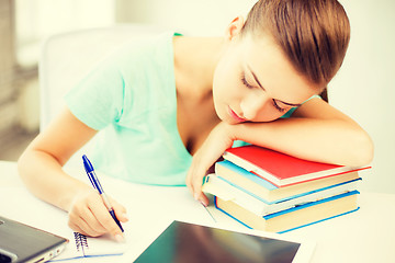 Image showing tired student sleeping on stock of books