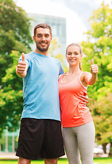 Image showing smiling couple showing thumbs up outdoors