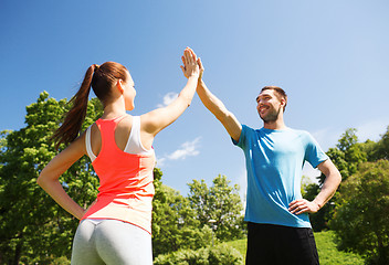 Image showing two smiling people making high five outdoors