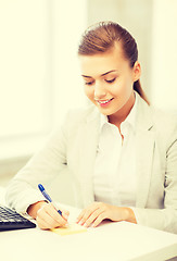 Image showing businesswoman writing on sticky note