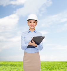 Image showing smiling businesswoman in helmet with clipboard