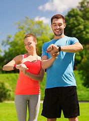 Image showing smiling people with heart rate watches outdoors