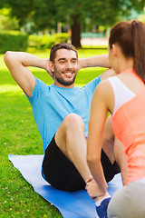 Image showing smiling man doing exercises on mat outdoors