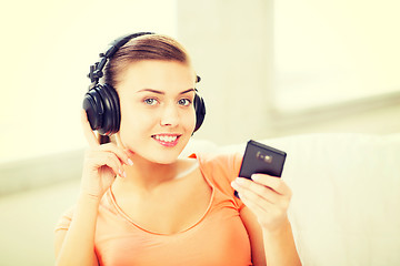 Image showing woman with headphones and smartphone at home