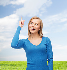 Image showing smiling woman pointing her finger up