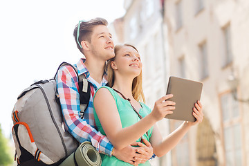 Image showing smiling couple with tablet pc and backpack in city