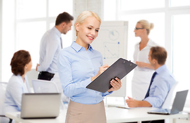 Image showing smiling businesswoman with clipboard and pen