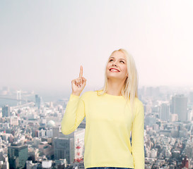 Image showing smiling woman pointing her finger up