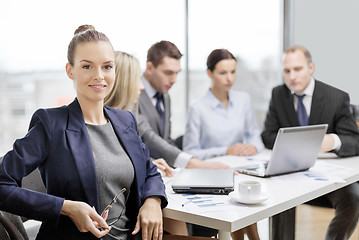 Image showing businesswoman with glasses with team on the back