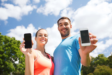 Image showing two smiling people with smartphones outdoors