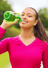 Image showing smiling woman drinking from bottle