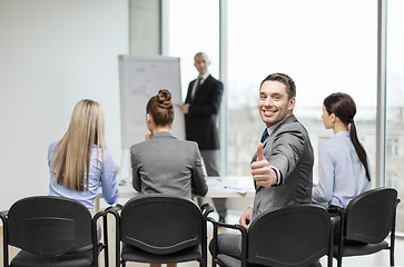 Image showing businessman with team showing thumbs up in office