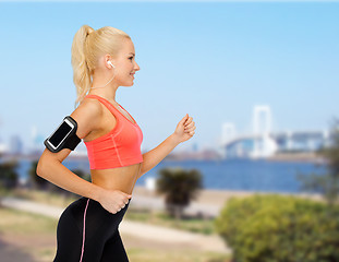 Image showing sporty woman running with smartphone and earphones