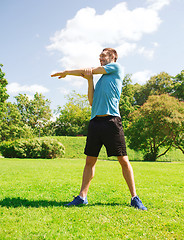 Image showing smiling man stretching outdoors