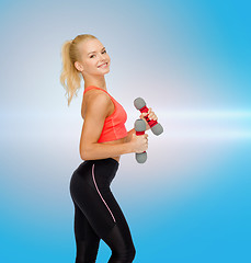 Image showing smiling beautiful sporty woman with dumbbells