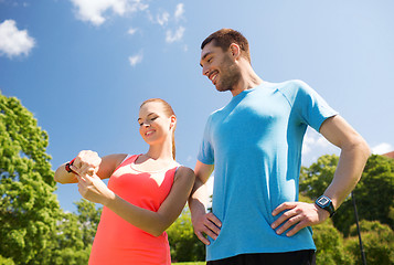 Image showing smiling people with heart rate watches outdoors