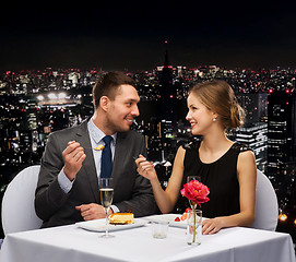 Image showing smiling couple eating dessert at restaurant