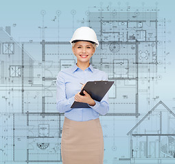 Image showing smiling businesswoman in helmet with clipboard