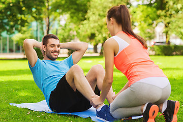 Image showing smiling man doing exercises on mat outdoors