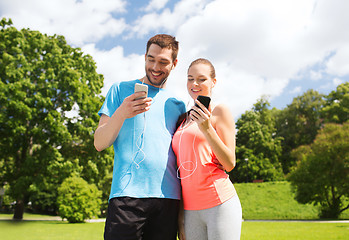 Image showing two smiling people with smartphones outdoors