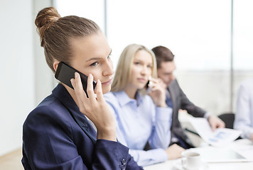 Image showing smiling business team with smartphones in office