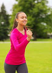 Image showing smiling young woman running outdoors