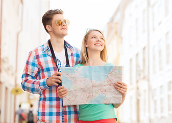 Image showing smiling couple with map and photo camera in city