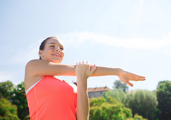 Image showing smiling woman stretching outdoors