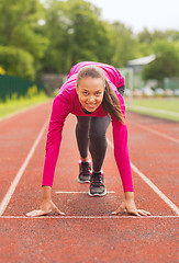 Image showing smiling young woman running on track outdoors