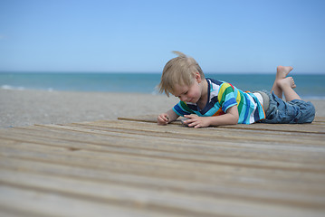 Image showing Boy laying down on a wooden walkway on the beach