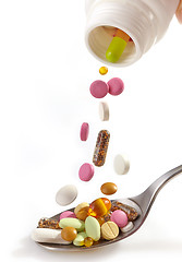 Image showing various pills falling into spoon