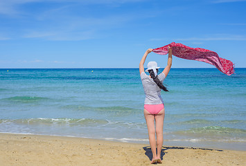 Image showing Young woman holding a fabric on windy beach