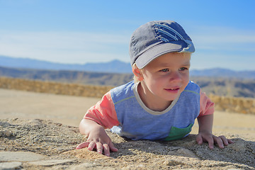 Image showing Little boy laying down on the rock