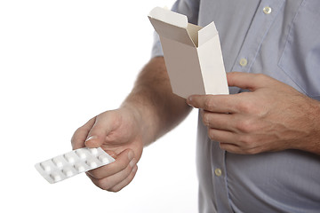 Image showing Man in a blue shirt takes pills