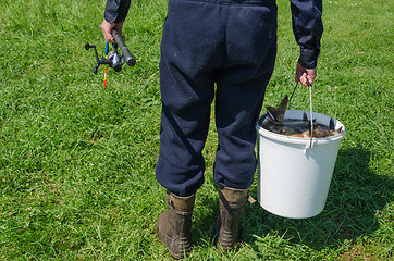 Image showing weary man hold bucket full of fishes and rod 