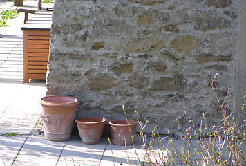 Image showing Three  plant pots in front of a stone wall