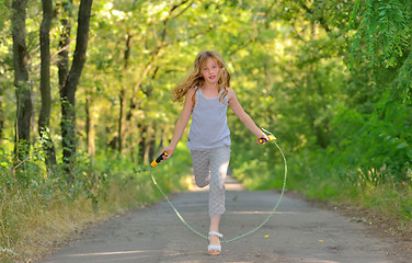 Image showing little girl jumps over rope