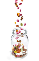 Image showing various medical pills falling into jar