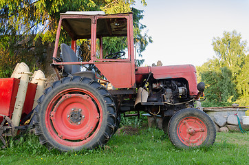 Image showing close up of rural tractor with red wheel in garden 