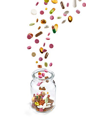 Image showing various medical pills falling into glass jar