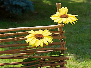 Image showing Artificial sunflowers on the decorative fence.