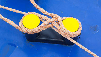 Image showing Twisted orange rope round a yellow bollard