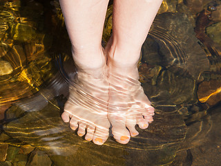 Image showing Dipping feet in water off a stone beach