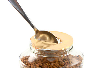 Image showing Ripping a hole in the foil of a jar of coffee with a teaspoon