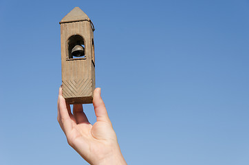 Image showing hand hold belfry miniature on blue sky background 